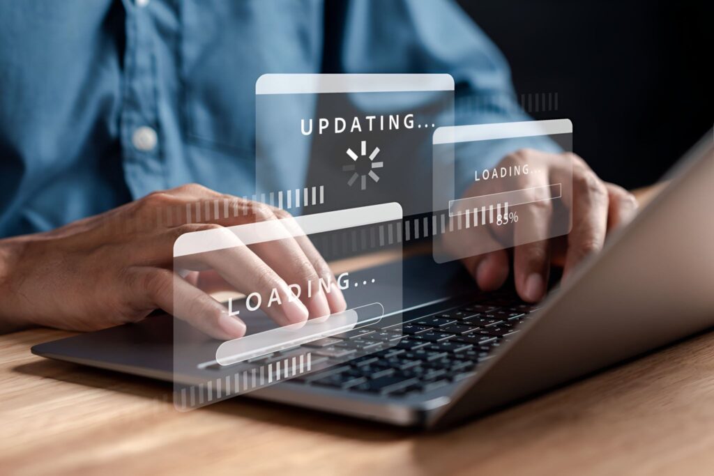 Person typing on a laptop as digital "Updating" and "Loading" panels appear on screen.