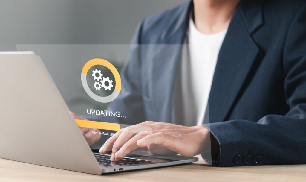 Close-up of hands on a laptop keyboard with a system update loading screen overlay